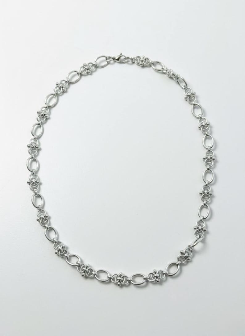 Overhead studio shot of a 60cm long industrial hardware-style necklace, showing the substantial 12mm width and secure lobster clasp closure.