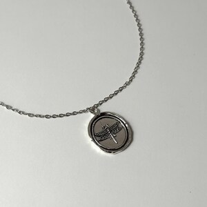 Whimsigoth Dragonfly Medallion Profile: A lifestyle shot of the silver-toned wax seal necklace worn on the chest, showcasing how the 35mm dragonfly pendant serves as a symbolic centerpiece.