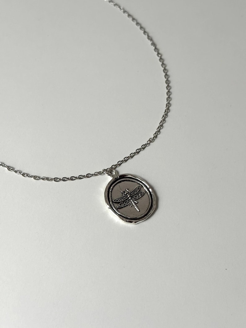 Whimsigoth Dragonfly Medallion Profile: A lifestyle shot of the silver-toned wax seal necklace worn on the chest, showcasing how the 35mm dragonfly pendant serves as a symbolic centerpiece.