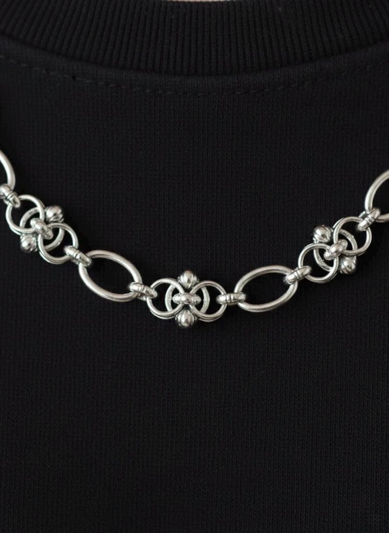 Extreme close-up of the stainless steel pierced jewelry links, detailing the high-quality craftsmanship and rugged industrial aesthetic of the chainmail weave.