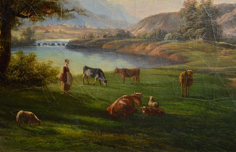 Op de afbeelding: Een schilderij dat een pastorale sc&egrave;ne voorstelt met een vrouw die in een veld staat met koeien en schapen. De sc&egrave;ne speelt zich af in een vallei met een rivier en bergen op de achtergrond. Het schilderij is gemaakt in een realistische stijl met gedempte kleuren.
