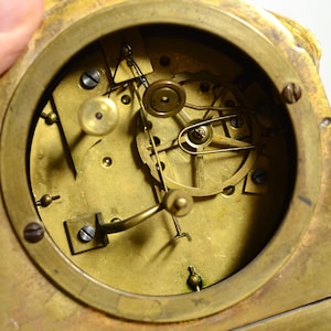 Puede incluir: Vista de cerca del funcionamiento interno de un reloj antiguo. La esfera del reloj est&aacute; hecha de lat&oacute;n y presenta una variedad de engranajes y muelles.