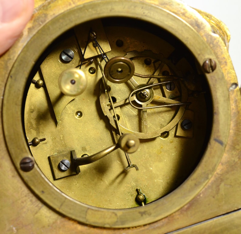 Puede incluir: Vista de cerca del funcionamiento interno de un reloj antiguo. La esfera del reloj est&aacute; hecha de lat&oacute;n y presenta una variedad de engranajes y muelles.