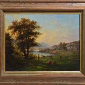Op de afbeelding: Een schilderij dat een landelijk landschap afbeeldt met een grote boom op de voorgrond, een rivier die door de sc&egrave;ne slingert en een groep koeien die grazen in een weiland. De lucht is zachtblauw met hints van roze en oranje, wat suggereert dat het zonsondergang of zonsopgang is.
