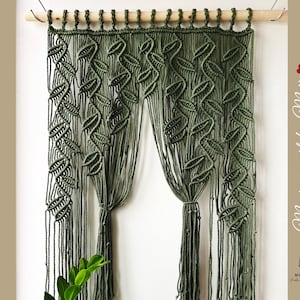May include: A green macrame wall hanging with a leaf pattern. The hanging is made of thick cord and has a wooden dowel at the top. The text "Macrame art by Meii" is visible on the right side of the image.