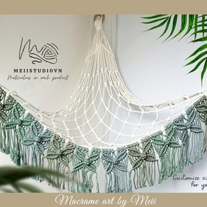 May include: A macrame hammock with a white net and green and blue fringe. The hammock is hanging from a white wall and has the text "Macrame art by Meii" and "Customize size/color for you" written below it.