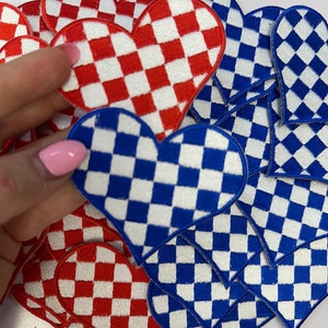 May include: A collection of red and blue checkered heart-shaped patches. The patches are made of fabric and have a white background with red or blue squares.