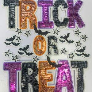 May include: A Halloween-themed decoration with the words "TRICK OR TREAT" spelled out in large, sequined letters. The letters are in black, orange, and purple, with a white border. Bats and stars are scattered around the words.