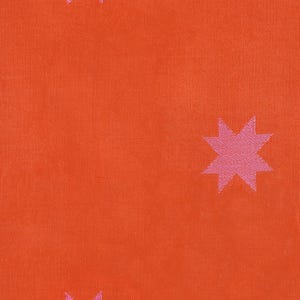 Puede incluir: Primer plano de una tela con un fondo naranja vibrante y patrones de estrellas rosas repetidos. La tela tiene una apariencia texturizada, con las estrellas espaciadas uniformemente en la superficie. La paleta de colores es brillante y llamativa.