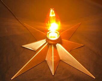 May include: A gold star-shaped lamp base with a warm, glowing light bulb in the center.