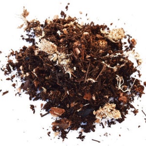 Op de afbeelding: Een close-up van een hoop bruine potgrond met kleine stukjes witte schors.