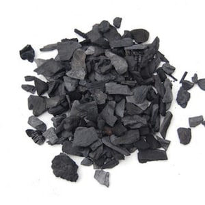 Puede incluir: Un montón de pequeños trozos de carbón vegetal negro.