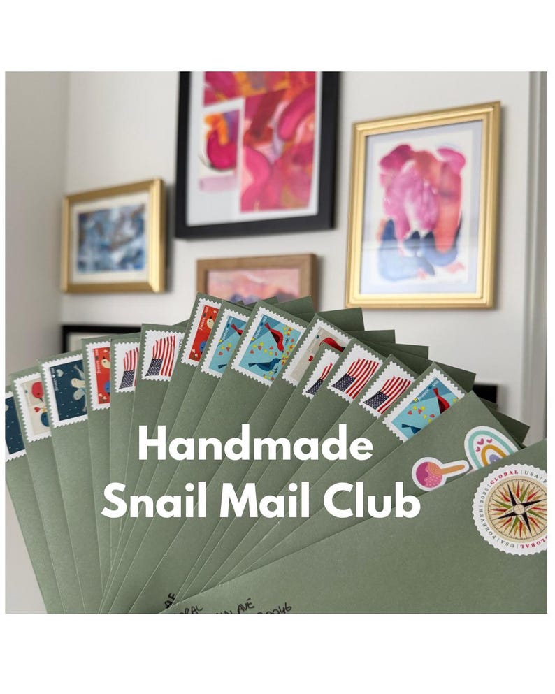 K&ouml;nnte beinhalten: Ein F&auml;cher aus gr&uuml;nen Umschl&auml;gen mit dekorativen Briefmarken, mit dem Text "Handmade Snail Mail Club". Die Briefmarken zeigen verschiedene Designs, darunter Flaggen und V&ouml;gel. Gerahmte Kunstwerke h&auml;ngen im Hintergrund.