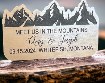 May include: A rustic brown card with a mountain silhouette design. The text reads "Meet us in the mountains Amy & Joseph 09.15.2024 Whitefish, Montana".
