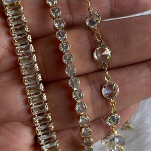 Puede incluir: Tres pulseras de oro con piedras de cristal transparentes. Las pulseras presentan diferentes estilos de piedras, incluyendo piedras de forma baguette y piedras redondas.