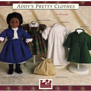 May include: A set of doll clothes for a 18-inch doll, including a blue school suit with a white blouse, a green winter coat, a white nightgown, a plaid tartan dress, and a kerchief bundle. The doll clothes are displayed on mannequins and a bag.