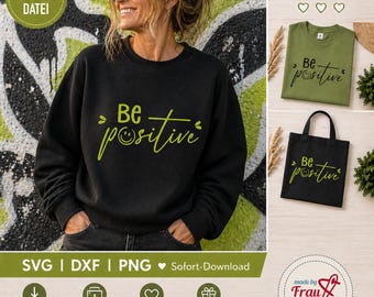 May include: A black sweatshirt with the words "Be positive" in a lime green script, with a smiling face replacing the "o". Also shown are a green t-shirt and a black tote bag with the same design.