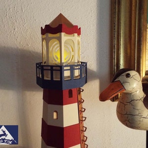 May include: A red and white striped lighthouse with a blue base and a white and yellow light house lantern. The lighthouse is made of paper and has a wooden base.