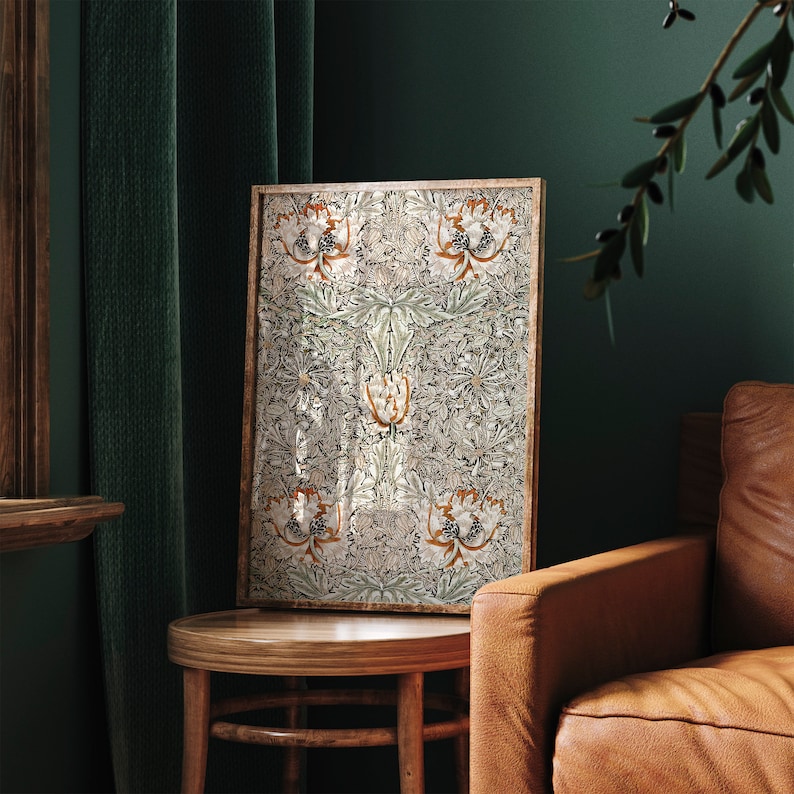 May include: A framed print with a floral pattern in shades of white, green, and brown. The print is hanging on a green wall next to a brown leather armchair.