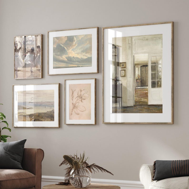 May include: A gallery wall featuring five framed prints. The prints depict a range of subjects, including a landscape, a still life, and a group of dancers. The frames are all wooden and have a light brown finish.