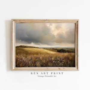 Peut inclure: Une impression d'art imprimable vintage d'un paysage avec un champ d'herbe et un ciel nuageux. L'impression est encadr&eacute;e dans un cadre en bois clair.