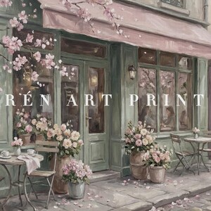 May include: An artistic painting of a cafe exterior with a pink awning and green trim. The storefront features large windows, tables, and chairs. The text "R&Eacute;N ART PRINT" is visible. Potted flowers and cherry blossoms add a touch of color.