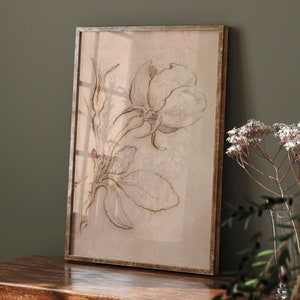 May include: A framed print of a delicate line drawing of a rose with leaves in shades of brown on a beige background.