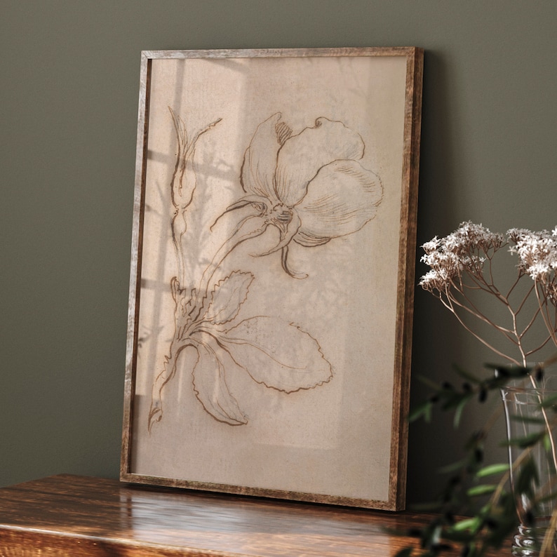 May include: A framed print of a delicate line drawing of a rose with leaves in shades of brown on a beige background.