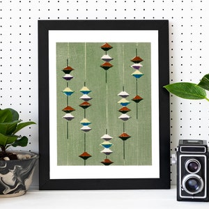 Puede incluir: Una impresi&oacute;n enmarcada de un dise&ntilde;o geom&eacute;trico abstracto con una serie de formas apiladas y superpuestas en tonos de marr&oacute;n, blanco, azul y verde sobre un fondo verde claro.