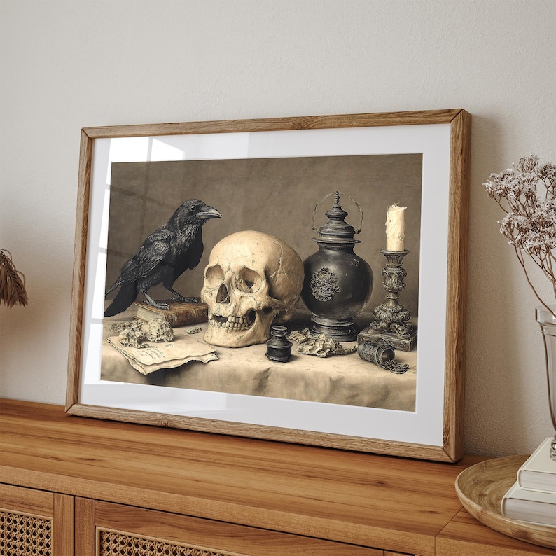 May include: A framed print featuring a still life with a skull, a black raven, and antique objects. The skull is centered, with a raven perched on a book to the left. A candle, lantern, and other items complete the composition.