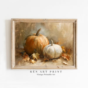 May include: A framed painting depicting two pumpkins, one orange and one white, with autumn leaves scattered around them. The painting has a vintage feel and is titled "RÉN ART PRINT Vintage Printable Art".