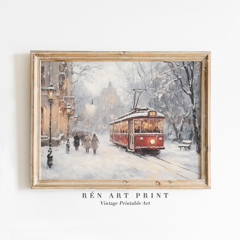 May include: A framed vintage print depicts a snowy street scene with a red tram car. The artwork features a winter landscape with figures walking along a snow-covered road, and street lamps illuminate the scene. The print is framed in a gold-colored wooden frame.