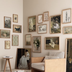 May include: A living room interior with a light beige wall featuring a gallery wall of framed artwork. The artwork includes a variety of styles and subjects, including landscapes, still lifes, and portraits. A brown leather armchair with a checkered fabric cushion sits in front of the gallery wall.