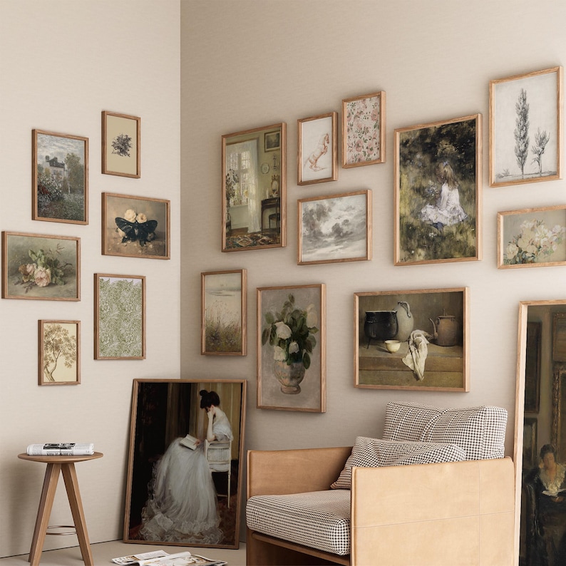 May include: A living room interior with a light beige wall featuring a gallery wall of framed artwork. The artwork includes a variety of styles and subjects, including landscapes, still lifes, and portraits. A brown leather armchair with a checkered fabric cushion sits in front of the gallery wall.