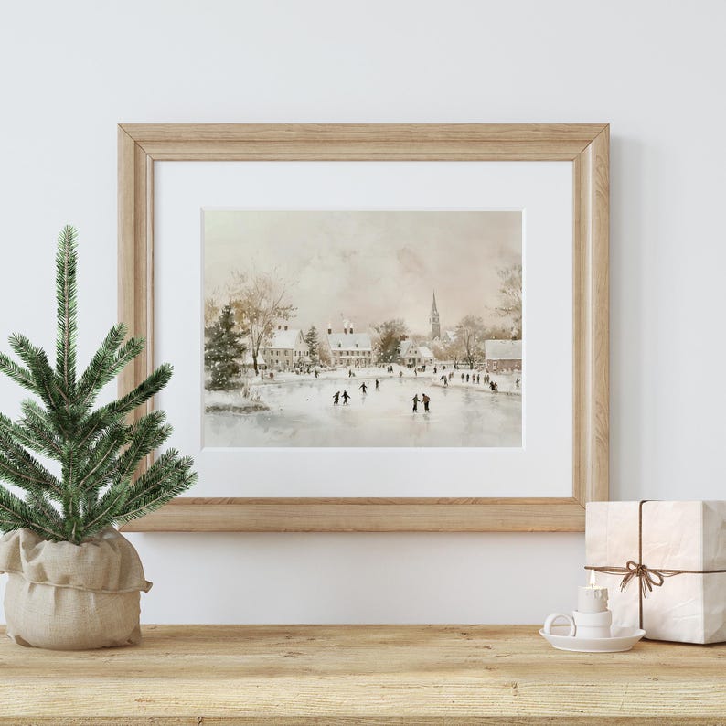 May include: A framed watercolour painting depicting a winter scene with people ice skating on a frozen lake in front of a small town. The painting has a soft, muted colour palette with shades of brown, grey, and white.