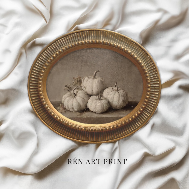 May include: An oval gold-toned frame with a fluted edge containing a monochromatic art print of four pumpkins. The print features a still life composition of light-colored pumpkins on a flat surface. The text R&Eacute;N ART PRINT is visible below.