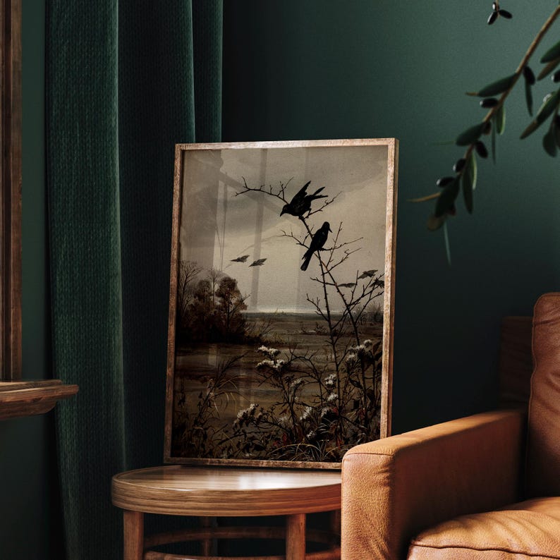 May include: A framed rectangular wall art print featuring a dark, moody landscape with two black birds perched on bare, thorny branches. The scene depicts a muted, sepia-toned marshland with distant trees under a cloudy, overcast sky.