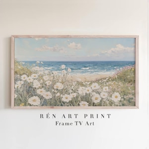 May include: A framed landscape painting of a beach scene. White flowers bloom in the foreground, with a sandy beach, blue ocean, and sky with clouds in the background. The text "R&Eacute;N ART PRINT Frame TV Art" is at the bottom.