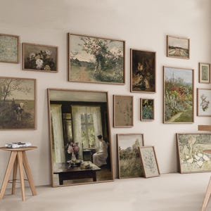 Op de afbeelding: Een galeriewand met een verscheidenheid aan ingelijste kunstwerken, waaronder landschappen, stillevens en portretten. De kunstwerken zijn symmetrisch gerangschikt op een witte muur.