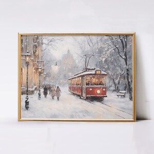 May include: Framed art print of a winter scene. A red trolley car travels down a snow-covered street lined with buildings and trees. Figures walk along the sidewalk. The artwork is in a gold frame.