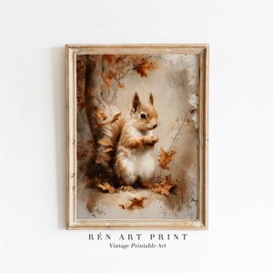 May include: A framed vintage art print depicting a squirrel in a forest. The artwork shows a brown and white squirrel surrounded by autumn leaves and a tree trunk. The print has a neutral colour palette with the text "RÉn Art Print" and "Vintage Printable Art".