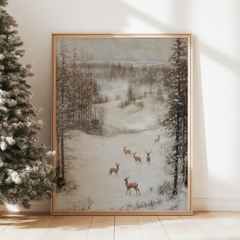 Op de afbeelding: Een ingelijst winterlandschapsschilderij met een kudde herten in een besneeuwd bos. Het kunstwerk heeft een gedempt kleurenpalet met tinten bruin, grijs en wit. Het schilderij zit in een houten lijst.