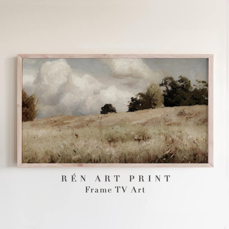 May include: A framed landscape art print featuring a serene field scene under a cloudy sky. The artwork showcases a grassy hill with trees and a soft color palette of beige, brown, and gray. The text "R&Eacute;N ART PRINT Frame TV Art" is at the bottom.