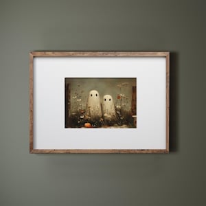May include: A framed art print featuring two white ghost figures with black dot eyes standing in a field of wildflowers and a small orange pumpkin. The artwork has a vintage, painterly style, perfect for Halloween decor.