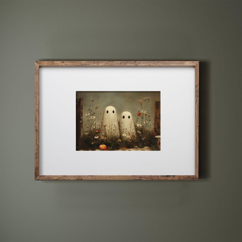 May include: A framed art print featuring two white ghost figures with black dot eyes standing in a field of wildflowers and a small orange pumpkin. The artwork has a vintage, painterly style, perfect for Halloween decor.