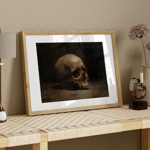 May include: A framed print of a black and white still life featuring a human skull on a dark background.