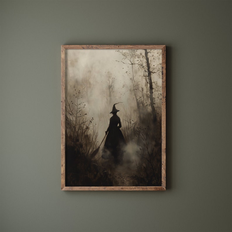 May include: A framed print showing a silhouetted witch in a forest, holding a broom. The artwork uses black, grey, and brown tones, creating a misty, atmospheric effect. The wooden frame provides a rustic element to the spooky scene.