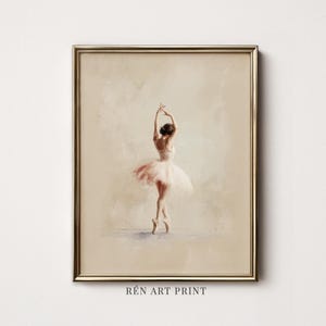 May include: A framed art print featuring a ballerina in a light pink tutu, captured in a dance pose with arms raised. The artwork is set against a soft, neutral beige background, and the text REN ART PRINT is visible at the bottom center.
