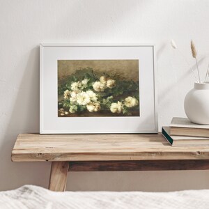 May include: A framed painting of a bouquet of white roses with green leaves on a brown background.