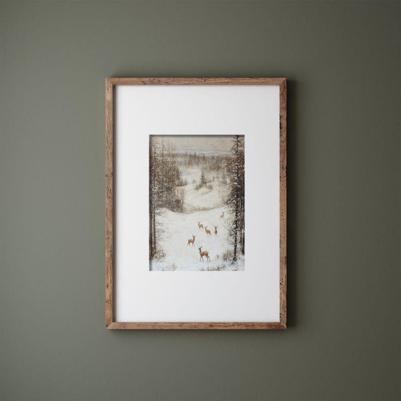 Op de afbeelding: Ingelijst kunstwerk met een winterlandschap met herten in een besneeuwde sc&egrave;ne. Het schilderij is gevat in een rustieke houten lijst met een witte passe-partout. Het kunstwerk toont een bos en een met sneeuw bedekt veld.